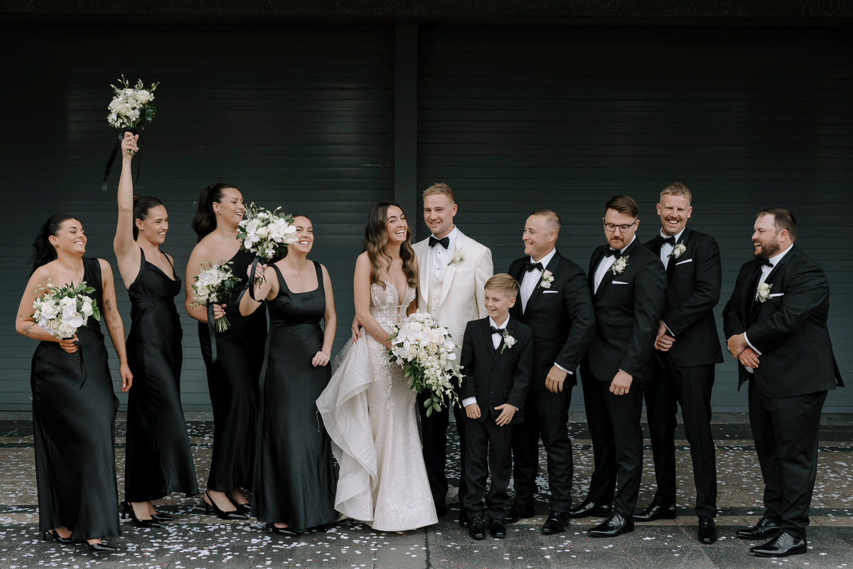 Bride in an ivory gown celebrating with her bridal party in black, Bespoke by Naked Sole