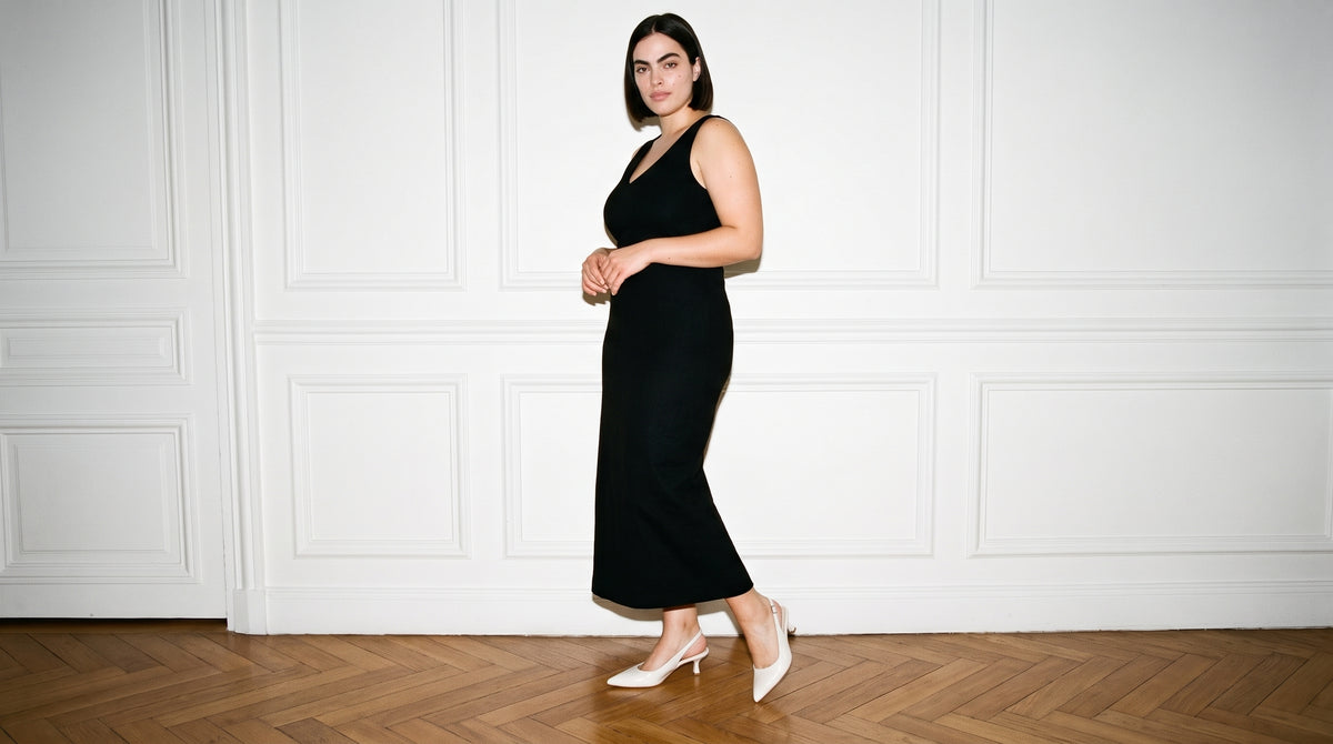 Woman in a black midi dress in a white panelled room wearing the Alexandra Wide Fit Slingback in white patent